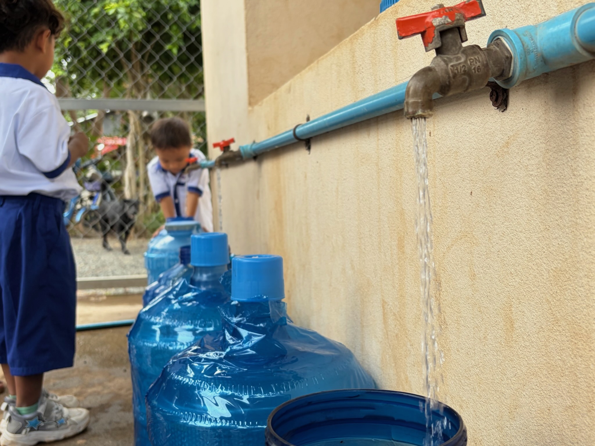 Students filling water containers from the newly installed school BioSand filter tap