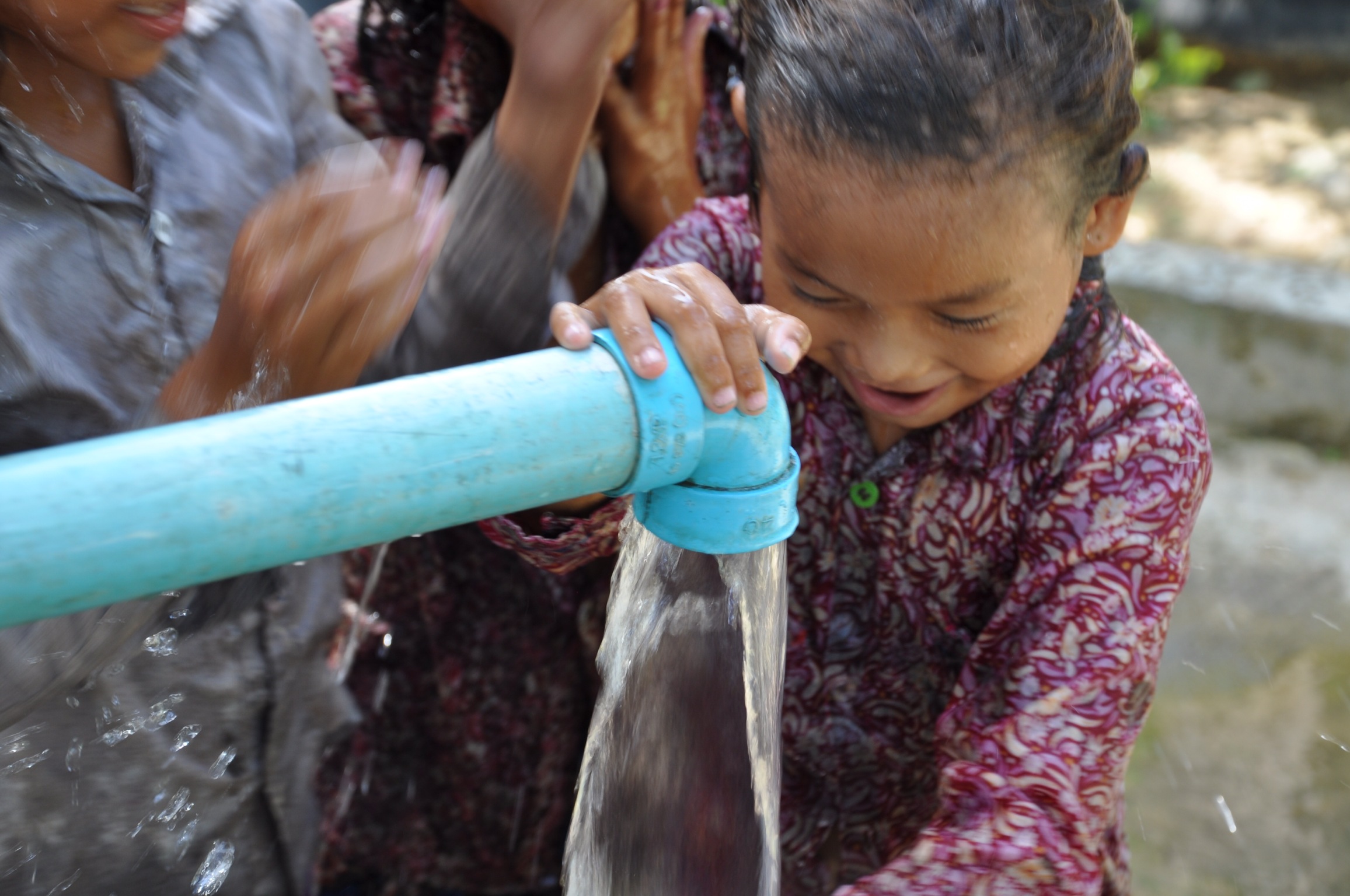 A young student drinking from the pipe of a new well at a Cambodian primary school, 2015