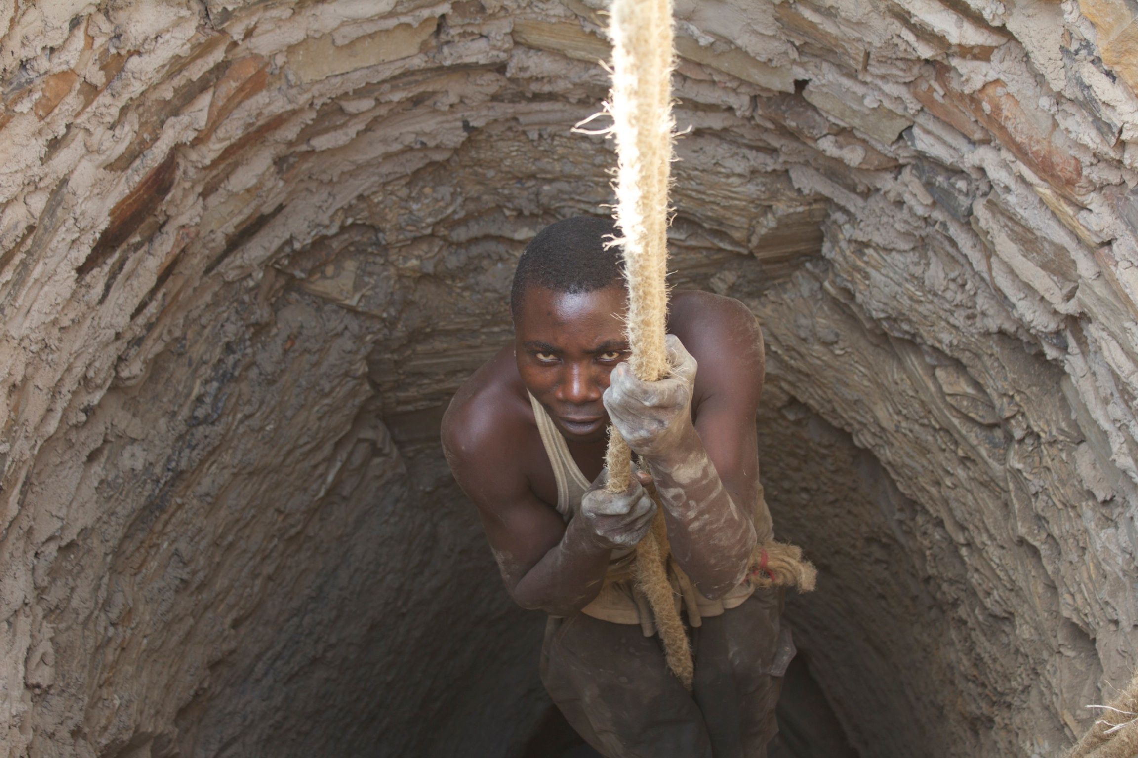Two men at the surface working the rope and pulley over the new well